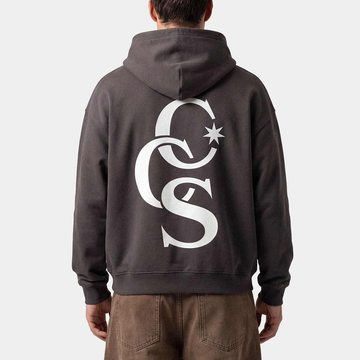 Close-up detail of the CCS Monogram charcoal hoodie by Caracas Merch worn by a model